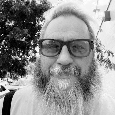 Jason, founder of New To Fishtown, a bearded man in glasses on a Fishtown sidewalk